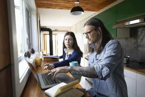 Couple working at home in small rustic kitchen Stock Photos