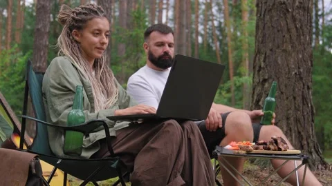 Couple working on a laptop computer while camping in the forest Stock Footage 327531190