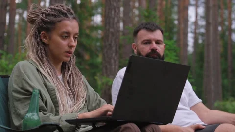 Couple working on a laptop computer while camping in the forest Stock Footage 327531261