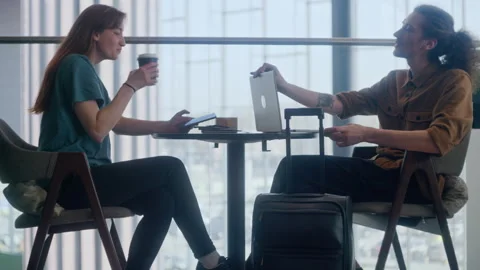 Couple Working or Relaxing with Computer, Drinks, and Suitcases at Airport Stock Footage 334567291