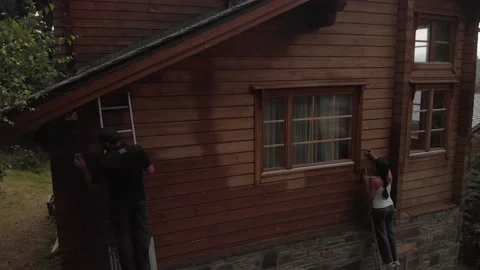 Couple working together on ladders sanding the facade of a chalet of stone an Vídeos de archivo 139096473