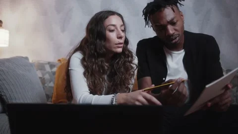 Couple working together, looking at a notepad together and talking Stockbeeldmateriaal 209255330