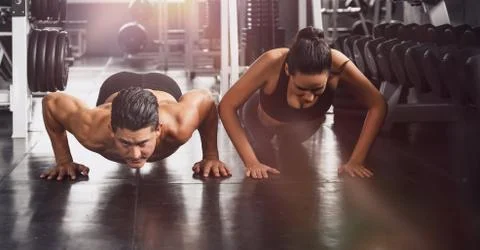 Couple workout and exercise by push ups in gym and fitness health club Stock Photos