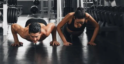 Couple workout and exercise by push ups in gym and fitness health club Stock Photos