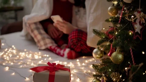 Couple wrapped blanket sit on bed Christmas pajamas using smartphone technology Stock Footage 252855767