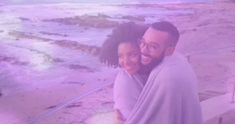 Couple wrapping in blanket by railing, cool breeze pulling hug, purple overlay Stock Footage 333893735