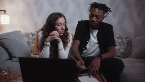 Couple writing in a notepad and talking while working out their bills Stockbeeldmateriaal 209256857