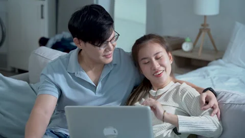 Couple of young asian using laptop together on sofa in living room at home. Stock Footage 252816129