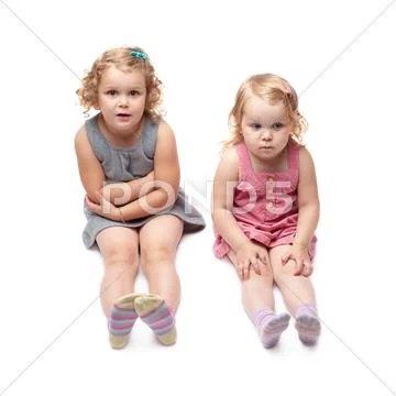 Couple of young little girl sitting over isolated white background Stock Photos
