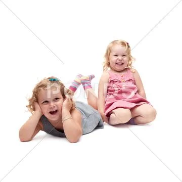 Couple of young little girls lying over isolated white background Stock Photos