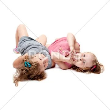 Couple of young little girls lying over isolated white background Stock Photos