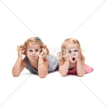Couple of young little girls lying over isolated white background Stock Photos