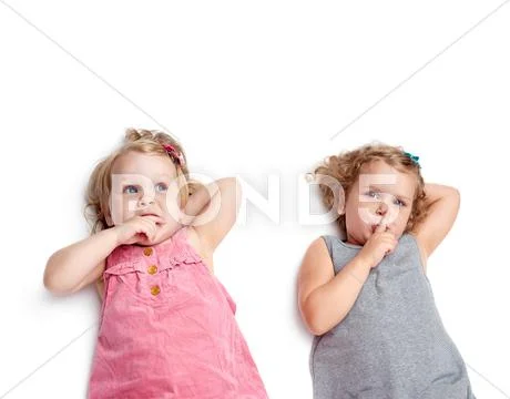 Couple of young little girls lying over isolated white background Stock Photos