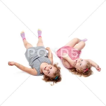 Couple of young little girls lying over isolated white background Stock Photos