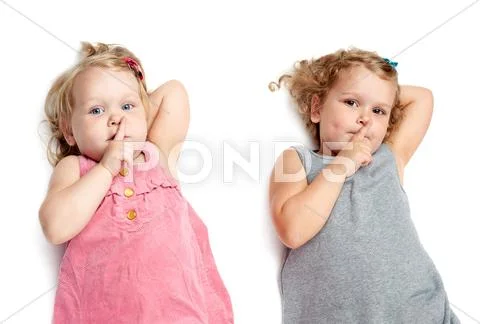 Couple of young little girls lying over isolated white background Stock Photos