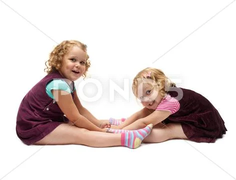 Couple of young little girls sitting over isolated white background Stock Photos