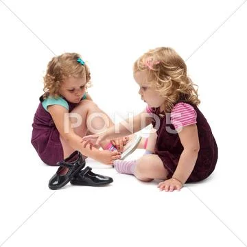 Couple of young little girls sitting over isolated white background Stock Photos