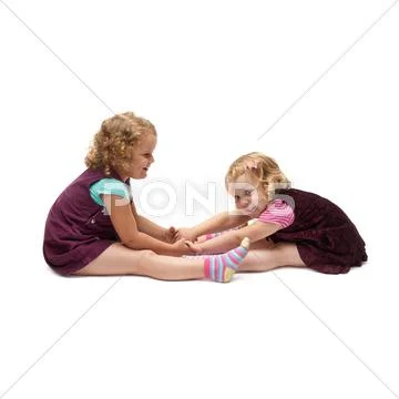 Couple of young little girls sitting over isolated white background Stock Photos