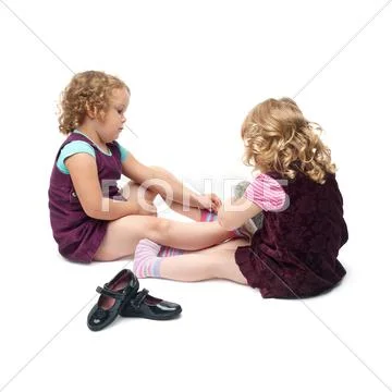 Couple of young little girls sitting over isolated white background Stock Photos