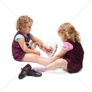 Couple of young little girls sitting over isolated white background Stock Photos