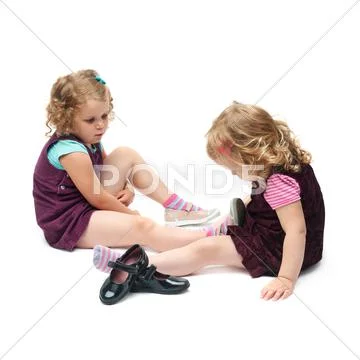 Couple of young little girls sitting over isolated white background Stock Photos
