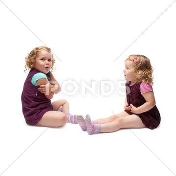 Couple of young little girls sitting over isolated white background Stock Photos