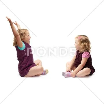 Couple of young little girls sitting over isolated white background Stock Photos