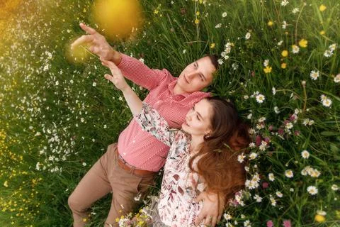 Couple of young people lying down on grass in field of flowers . Stock Photos