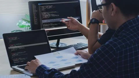 Couple Young programmer writing program code sitting at the workplace with .. Photos