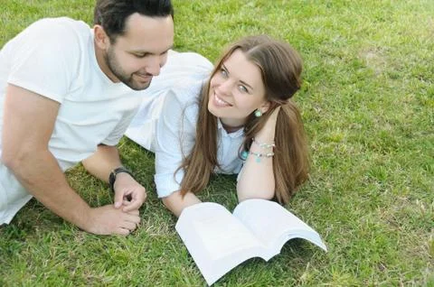 Couple of young students studing on the grass by the campus Stock Photos