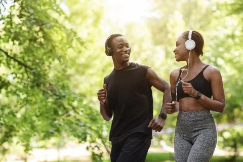 Couples Active Leisure. Happy Black Guy And Girl Jogging Together Outdoors Stock Photos
