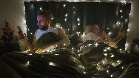 Couples enjoying nighttime relaxation with string lights in bedroom Stock Footage 303797677