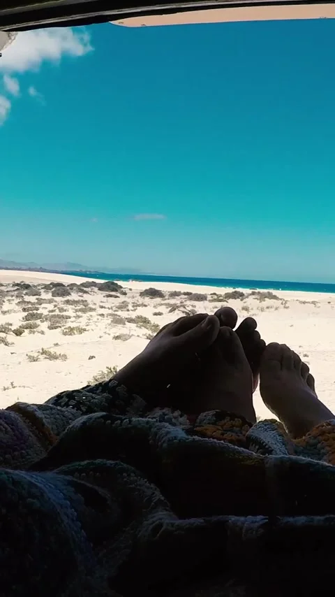 Couple's feet stick out from under a blanket as an automatic roller blind Stock Footage 344842078