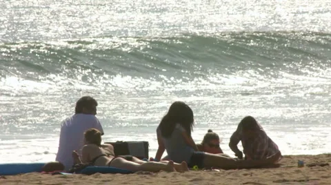 COUPLES LAYING ON BEACH WATCHING BIG WAVES Stock Footage 5655895