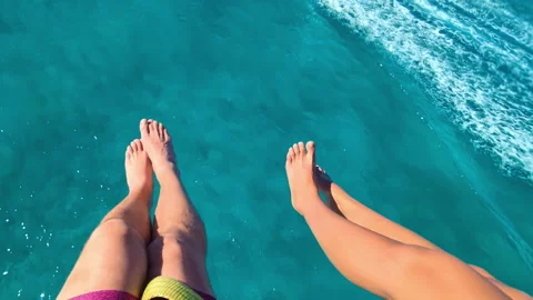 Couple's Legs Dangle Above Turquoise Waters from an Exhilarating Stock Footage 265881268