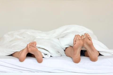 A couple's legs entangled in bed, capturing the intimacy of their moment Stock Photos