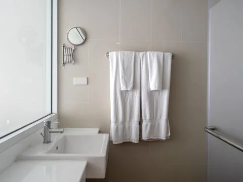 Couples set of large and small clean white towels folded hanging on a metal.. Stock Photos