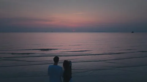 Couples watching sunset on peaceful beach. Videographer is capturing footage of Stock Footage 312748079