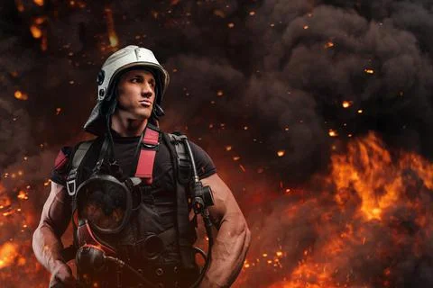 Courageous fireman with hard hat looking away against flame 库存照片