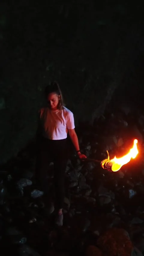 Courageous young woman exploring the dark Guincho cave. She holds a flaming Stock Footage 339832712