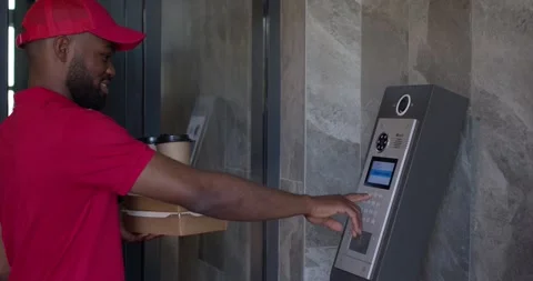 Courier african man doing fast food delivery, dials the house number in intercom Stock Footage 261674505