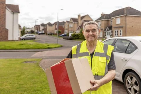 Courier Approaching Home While Carrying Online Shopping Parcel for Delivery Foto stock