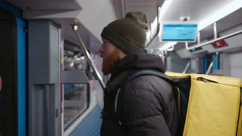 Courier with a backpack is standing at the door in the subway car. Manual camera Stock Footage 236089421