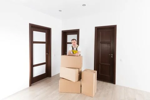 Courier with boxes in empty apartment. Delivery service theme. Stock Photos