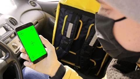 Courier in the car is on his phone, backpack for orders on the seat. Food Stock Footage 148651885