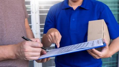 Courier delivery man checking or holding cardboard parcel package to deliver Stock Photos