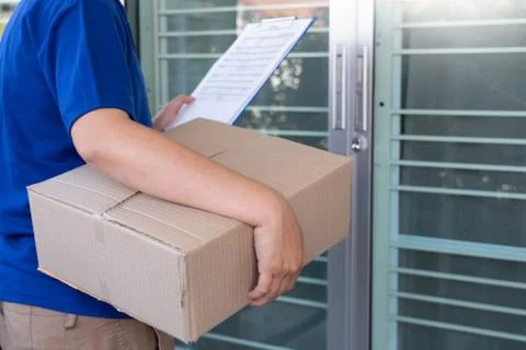 Courier delivery man checking or holding cardboard parcel package to deliver Stock Photos