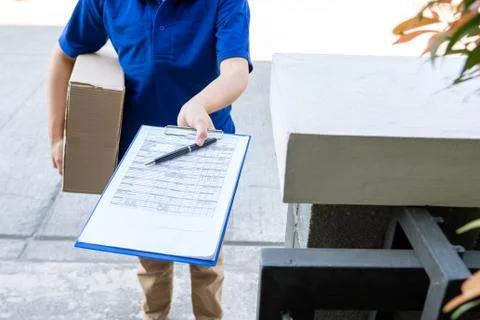 Courier delivery man checking or holding cardboard parcel package to deliver Stock Photos
