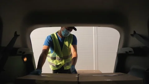 Courier delivery man delivers parcels by car. A volunteer loads cardboard boxes Stock Footage 138596010