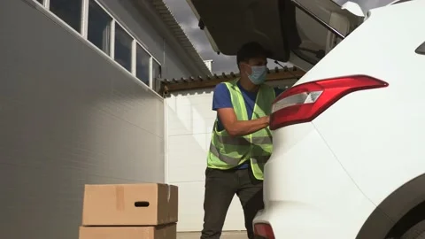 Courier delivery man delivers parcels by car. A volunteer loads cardboard boxes Stockbeeldmateriaal 138596016